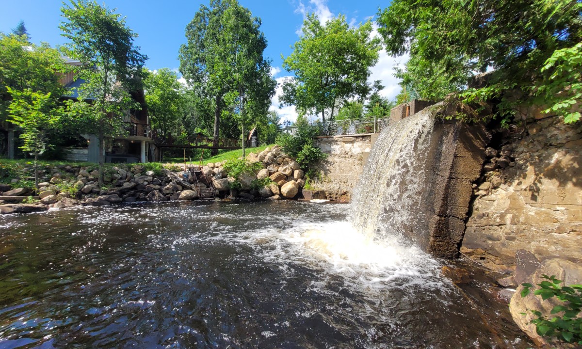 Vue verticale d’un ouvrage de retenue séparant un plan d’eau et un écoulement naturel en milieu boisé  à Sainte-Agathe-des-Monts